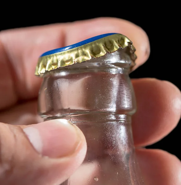 Glass bottle with a cap in his hand on a black background — Stock Photo, Image