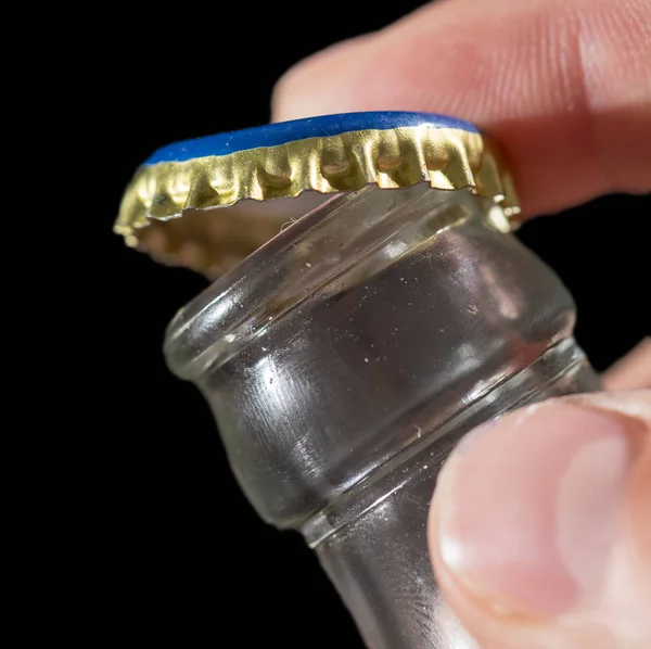 Glass bottle with a cap in his hand on a black background — Stock Photo, Image