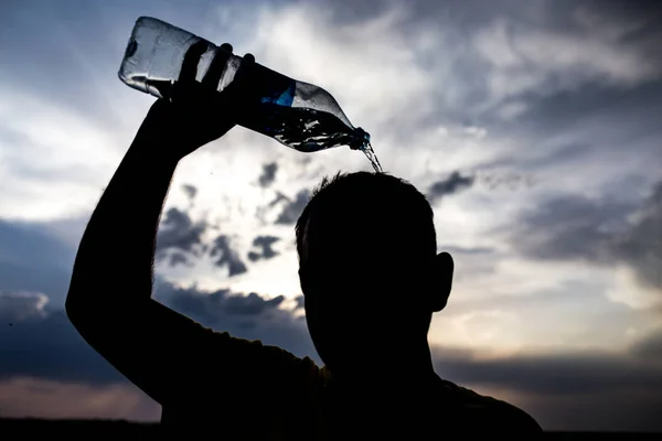 Man pours water on his head in the sunset — Stock Photo, Image