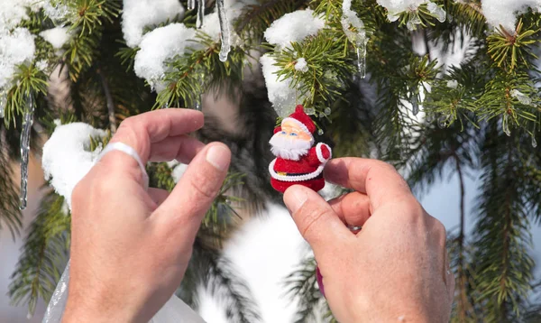 Man hangs a toy on the Christmas tree in winter — Stock Photo, Image