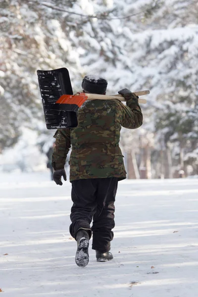 Trabajador limpia la pala de nieve en la naturaleza — Foto de Stock