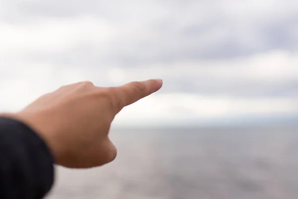 Mans kéz a háttérben a tenger, a felhők — Stock Fotó