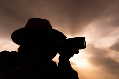 Günbatımı arka planında kamera olan bir adamın silueti.