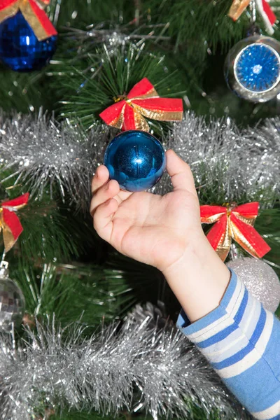 Juguete en el árbol de Navidad en una mano de niños para el Año Nuevo —  Fotos de Stock