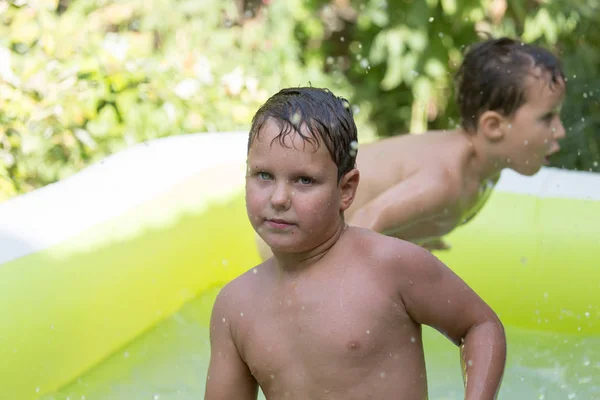 Два мальчика вылили воду из бассейна на природе — стоковое фото