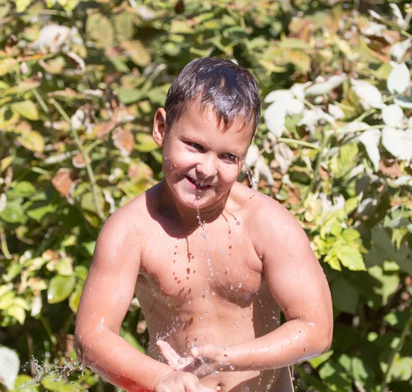 Pojke häller vatten från poolen i naturen — Stockfoto