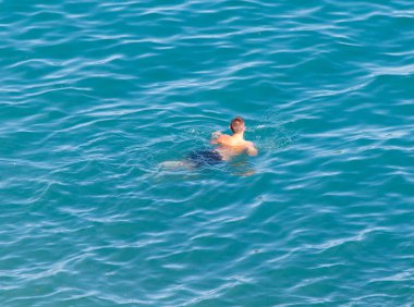 Adam sahildeki gölde banyo yapıyor.