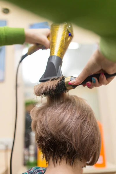 美容師はヘアドライヤーブロンドの髪を乾かします — ストック写真