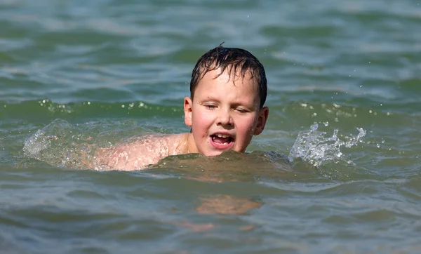 Pojke badar i sjön till stranden — Stockfoto