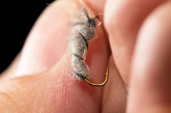 Vliegen om vis te vangen in een hand op een zwarte achtergrond — Stockfoto