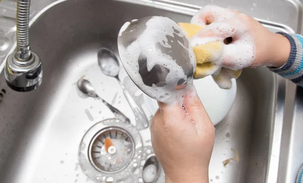 Мальчик моет посуду на кухне — стоковое фото
