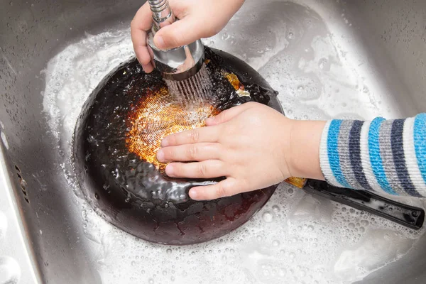 Хлопчик миє посуд на кухні — стокове фото