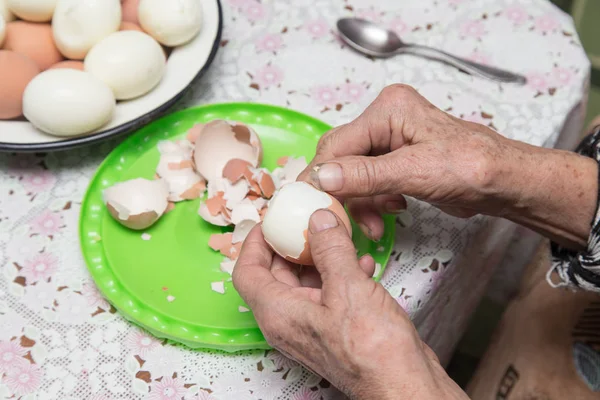 Granny cleans eggs — Stock Photo, Image