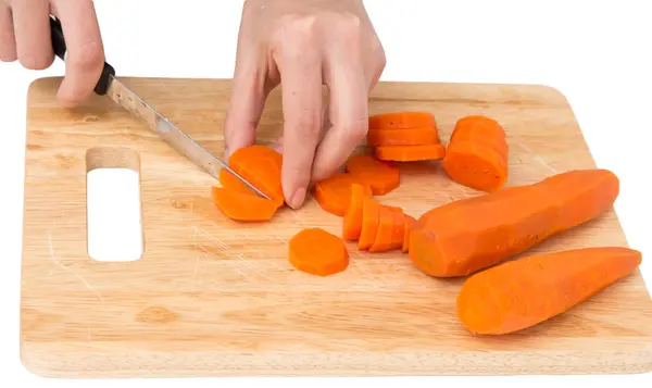 Повар режет морковь на белом фоне — стоковое фото