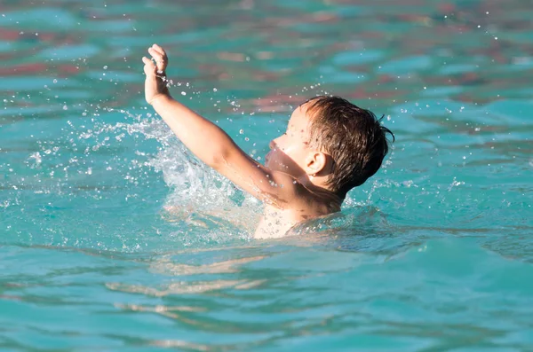 Мальчик плавает с брызгами в аквапарке — стоковое фото