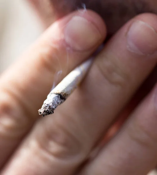 Pali papierosa w dłoni — Zdjęcie stockowe