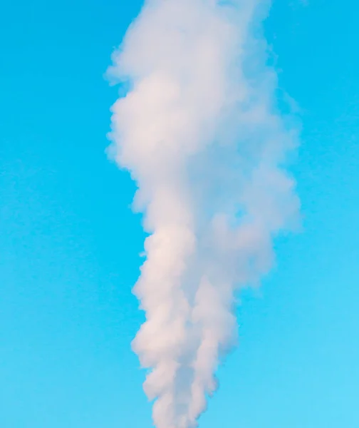 Белый промышленный дым из дымохода на голубом небе — стоковое фото