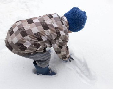 Çocuk kışın karla oynuyor.