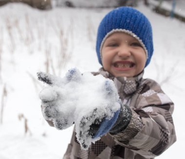 Çocuk kışın karla oynuyor.