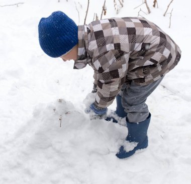 Çocuk kışın karla oynuyor.