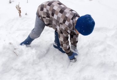 Çocuk kışın karla oynuyor.