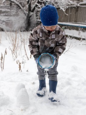 Çocuk kışın karla oynuyor.