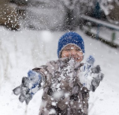 Çocuk kışın karla oynuyor.