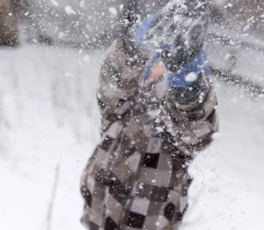 Çocuk kışın karla oynuyor.