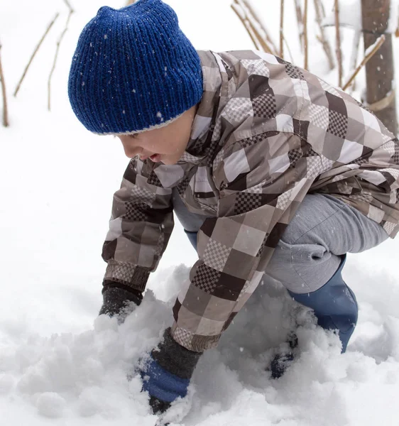 Çocuk kışın karla oynuyor.