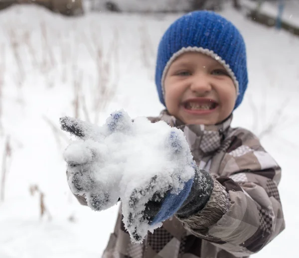 Çocuk kışın karla oynuyor.