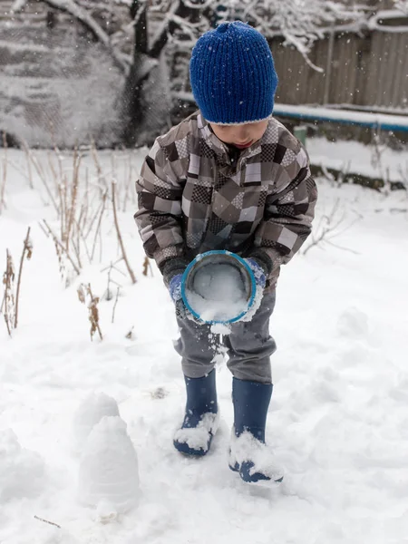 Çocuk kışın karla oynuyor.