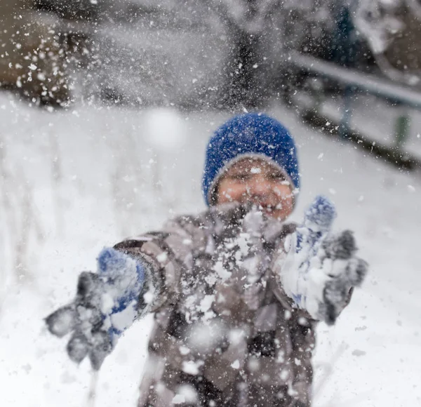 Çocuk kışın karla oynuyor.