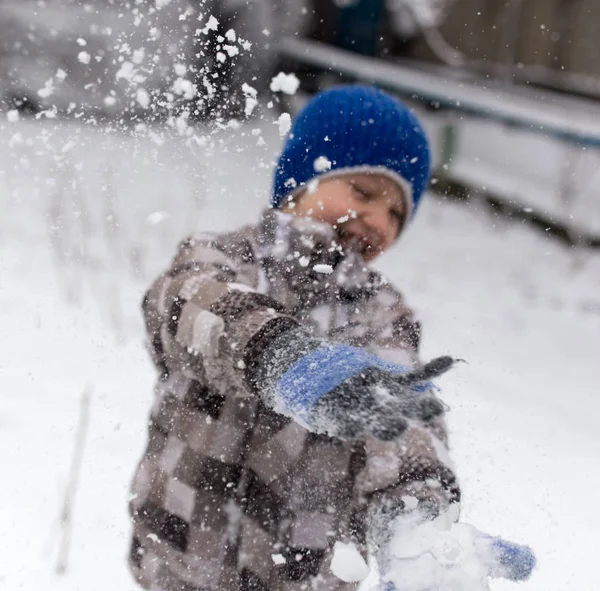 Çocuk kışın karla oynuyor.