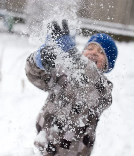 Chłopiec bawi się śniegiem w zimie — Zdjęcie stockowe