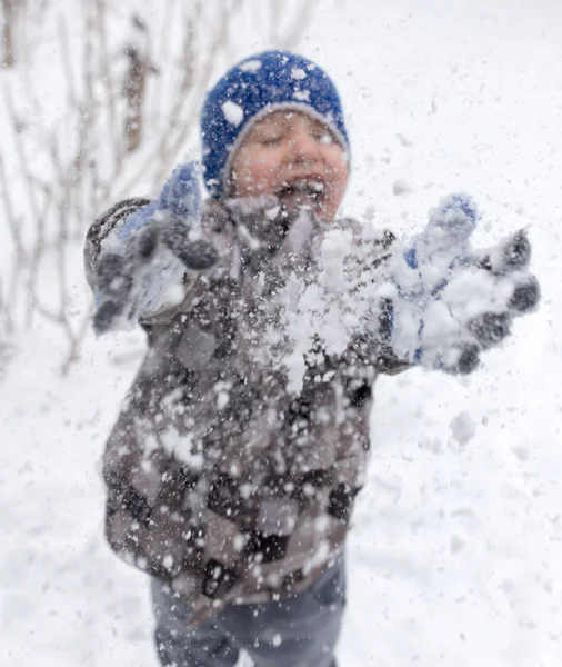 Çocuk kışın karla oynuyor.
