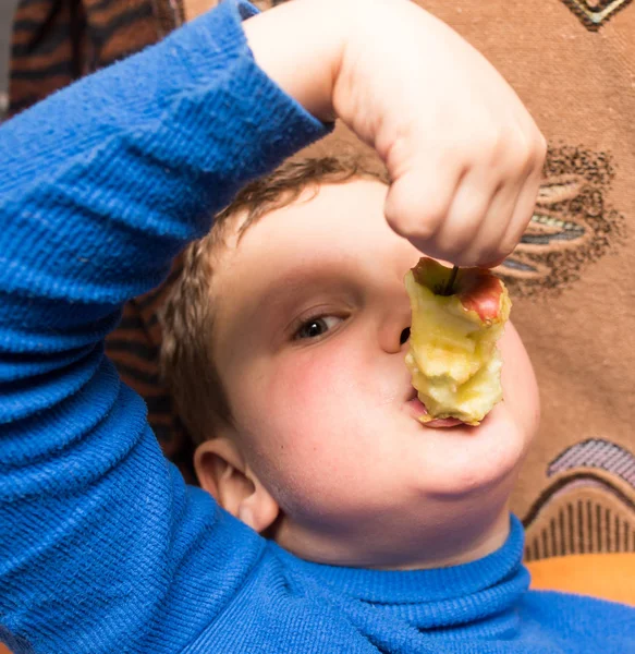 Un garçon mange une pomme — Photo