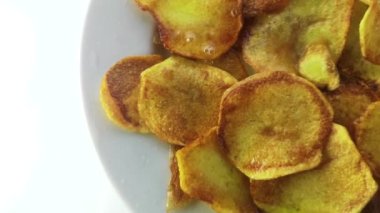 Beyaz tabakta yağda kızartılmış patates cipsi..