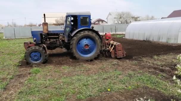 村の庭で地面を耕すトラクターの映像 — ストック動画