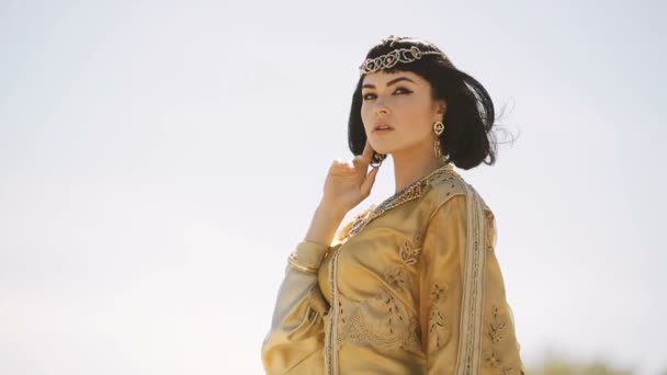 Bella donna con trucco di moda e acconciatura come la regina egiziana Cleopatra all'aperto contro il deserto tempo ventoso — Video Stock