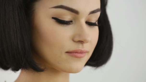 Chica sonriente con Cleopatras maquillaje y corte de pelo mirando a la cámara — Vídeos de Stock