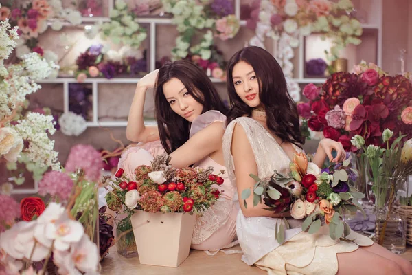 Красивые азиатки-флористки работают в цветочном магазине с большим количеством весенних цветов — стоковое фото