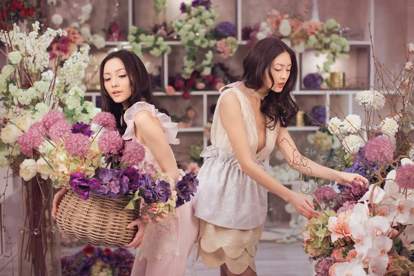 Belle donne asiatiche fioristi felici di lavoro nel negozio di fiori con un sacco di fiori primaverili — Foto Stock