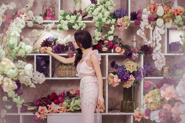 Schöne asiatische Blumenhändlerin in rosa Kleid in Blumenladen — Stockfoto