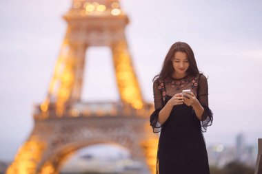 Eyfel Kulesi ve carousel, Paris yakınlarında Smartphone kullanan kadın seyahat. Küçük görüntü akşam.