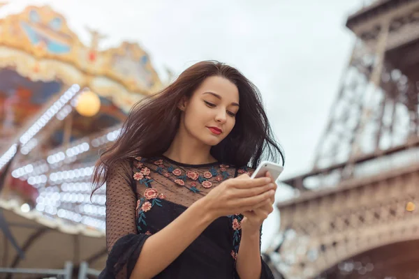 Cestovní žena pomocí smartphone poblíž Eiffelova věž a kolotoč, Paříž. — Stock fotografie