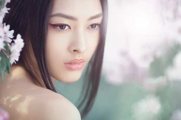 Portret van een Aziatische meisje van de mooie fantasie buitenshuis tegen natuurlijke lente bloem achtergrond. — Stockfoto