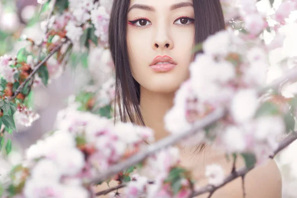 Retrato de una hermosa chica asiática al aire libre contra el árbol de flores de primavera . — Foto de Stock