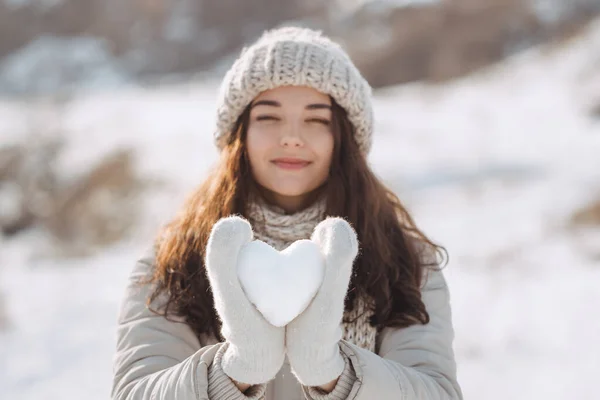 Snö hjärta i händerna på en kvinna — Stockfoto