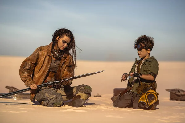 Пост Апокаліптична жінка і хлопчик зі зброєю на відкритому повітрі в пустелі — стокове фото