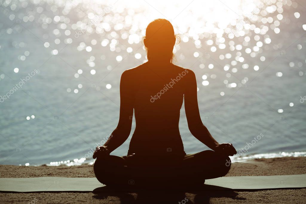Silhouette of a Woman in Meditation on the Beach